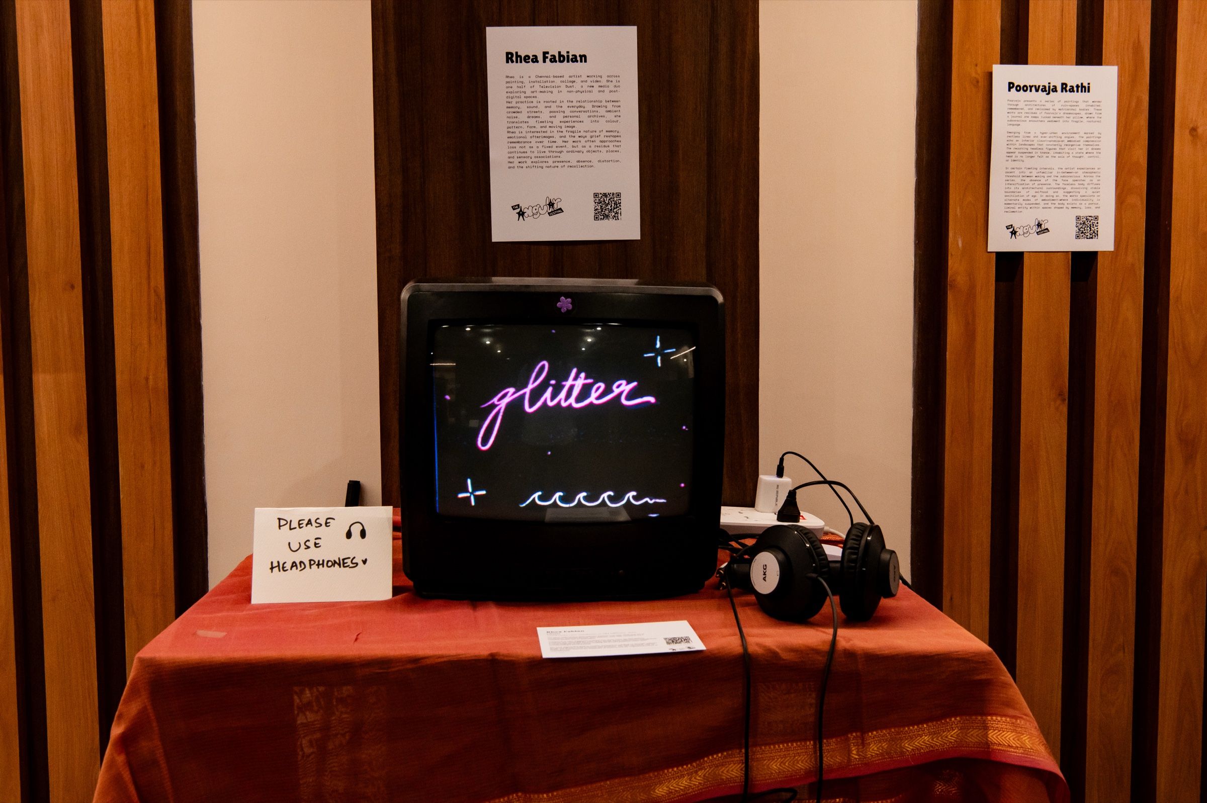 Glitter playing on a CRT television beside headphones and a handwritten listening instruction.