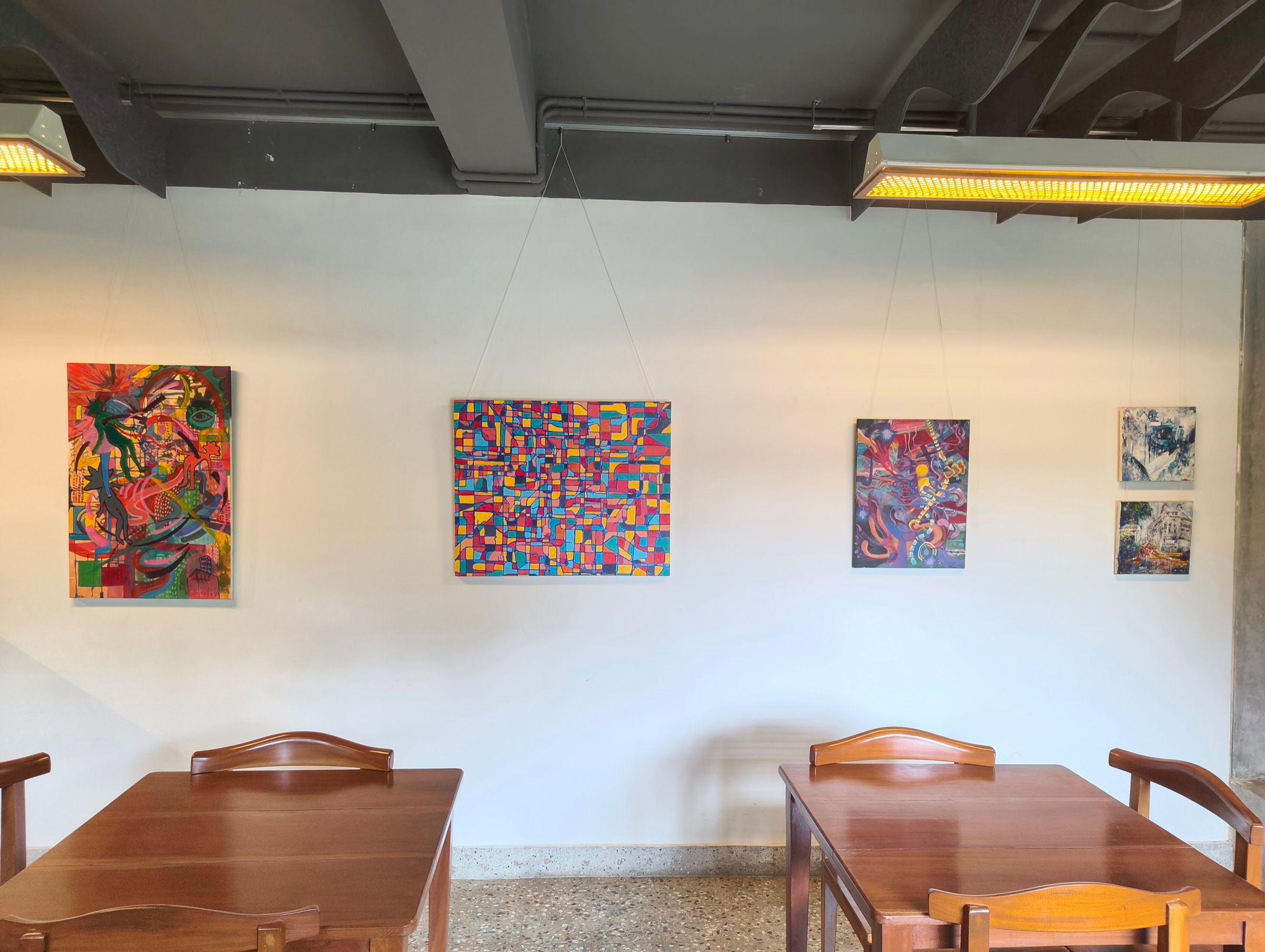 Five colourful Human Music paintings installed above wooden tables at Vinyl & Brew.