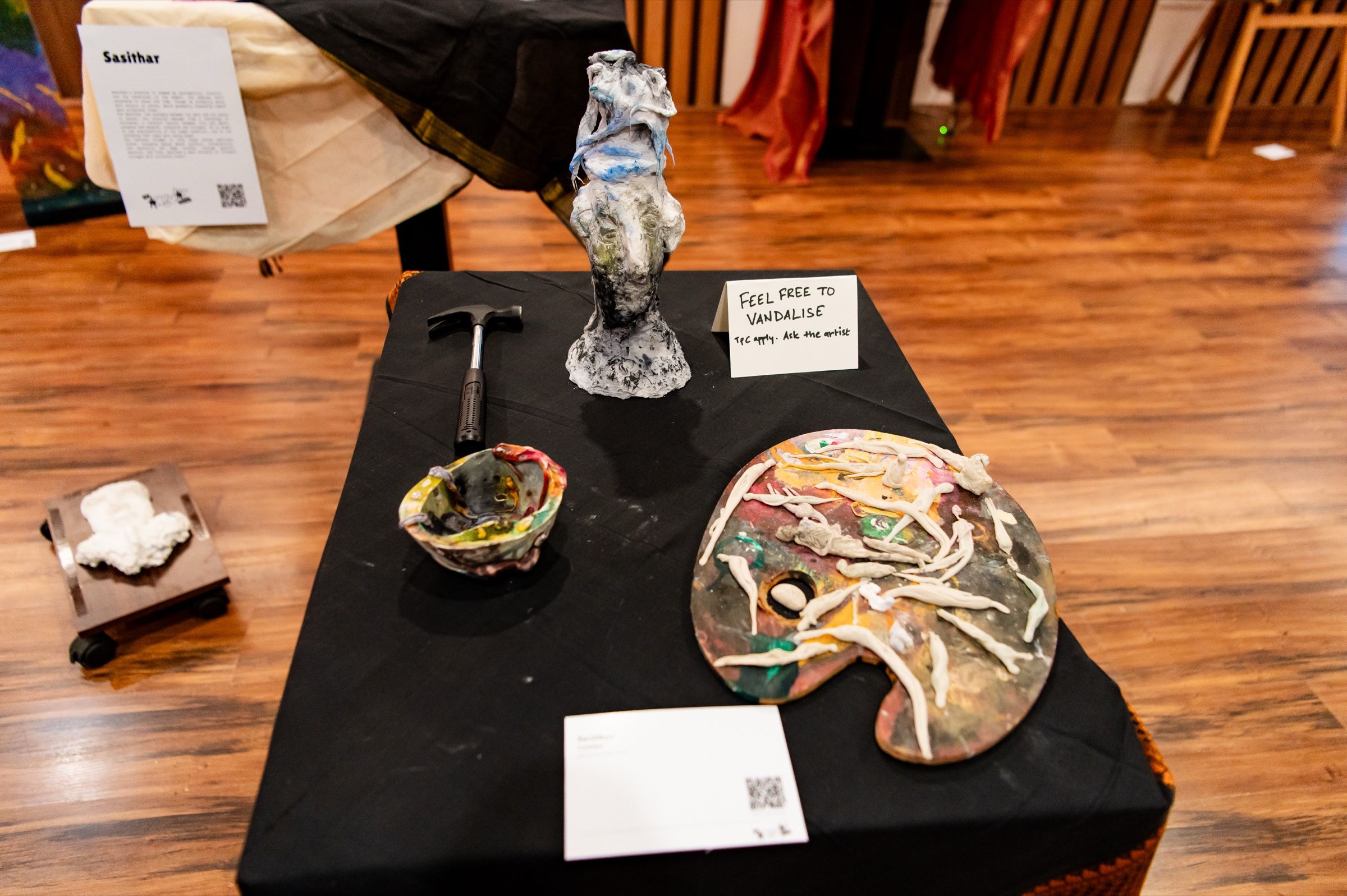 A sculptural figure, hammer and marked palette displayed with an invitation to vandalise the work.