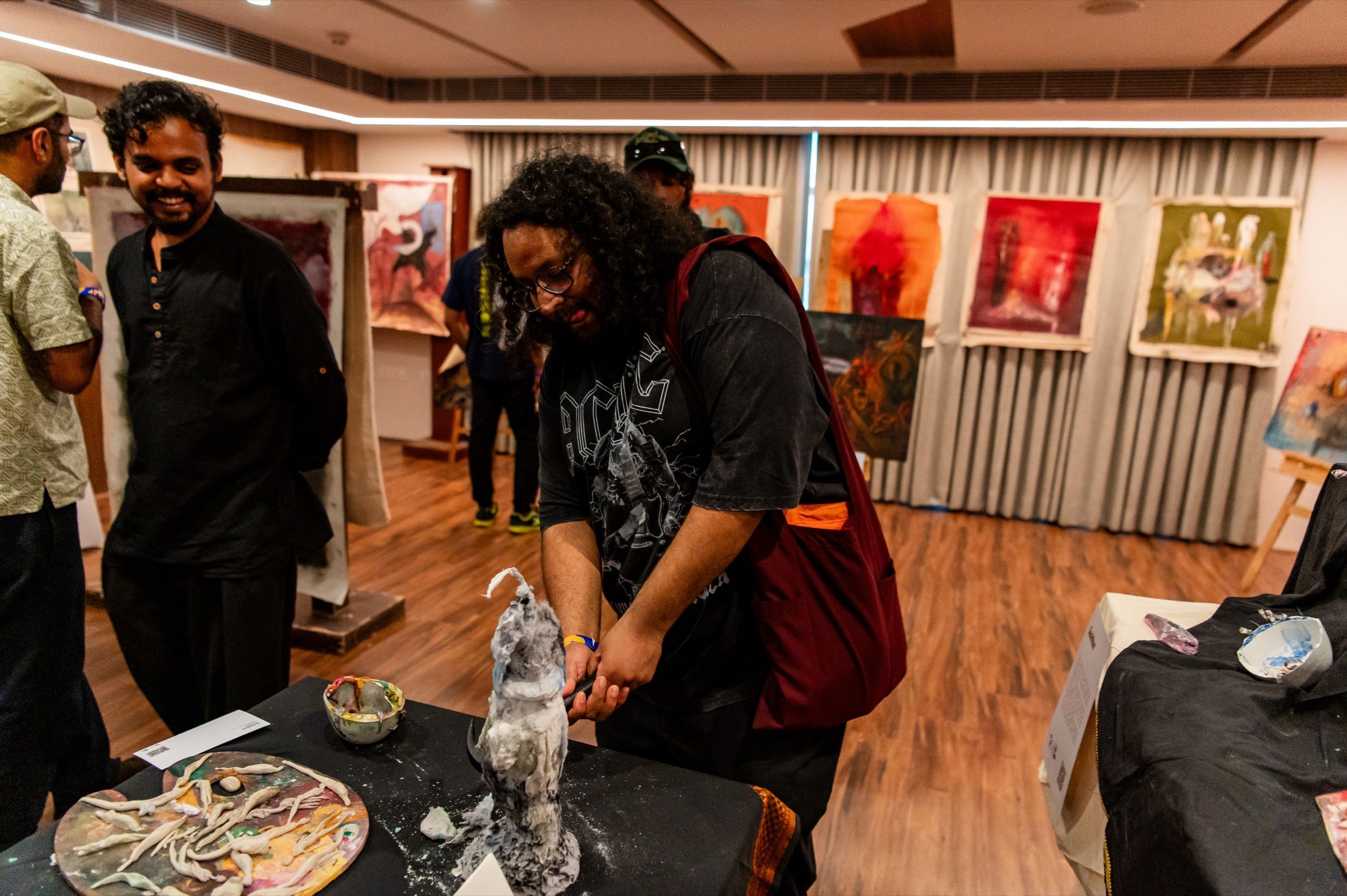 A visitor uses a hammer on the participatory sculpture while others watch.