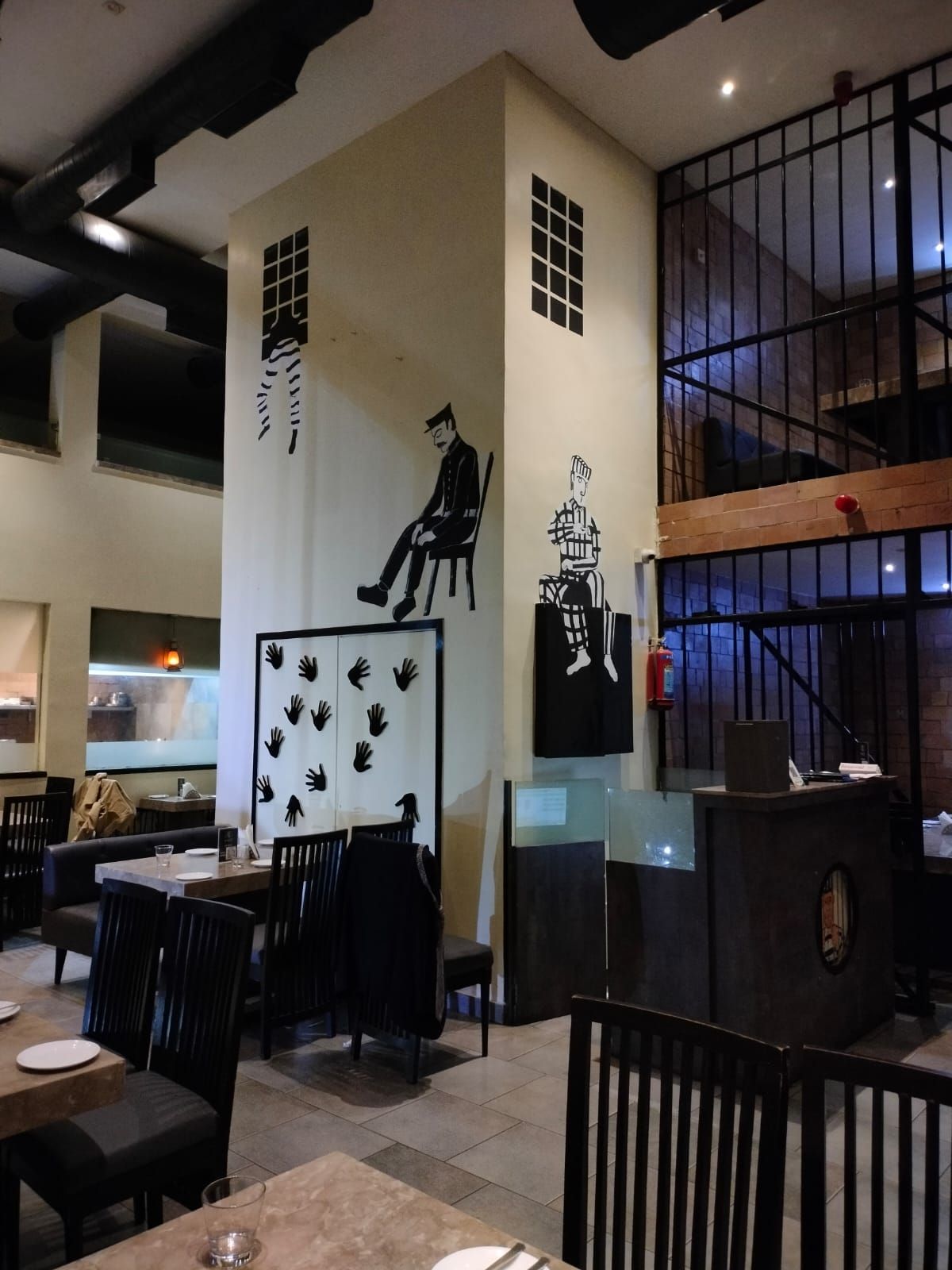Black-and-white prison-themed murals painted across tall walls inside Kaidi Kitchen.