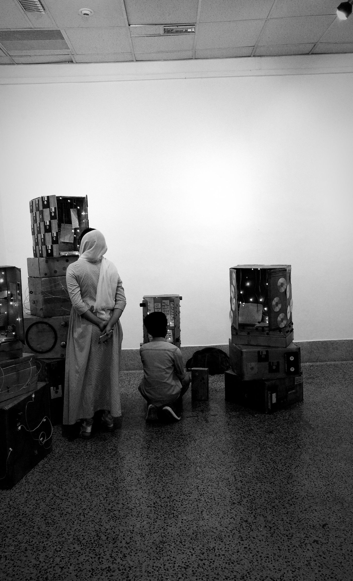 Two visitors examine the cardboard shrine structures in Museum of Leftovers.
